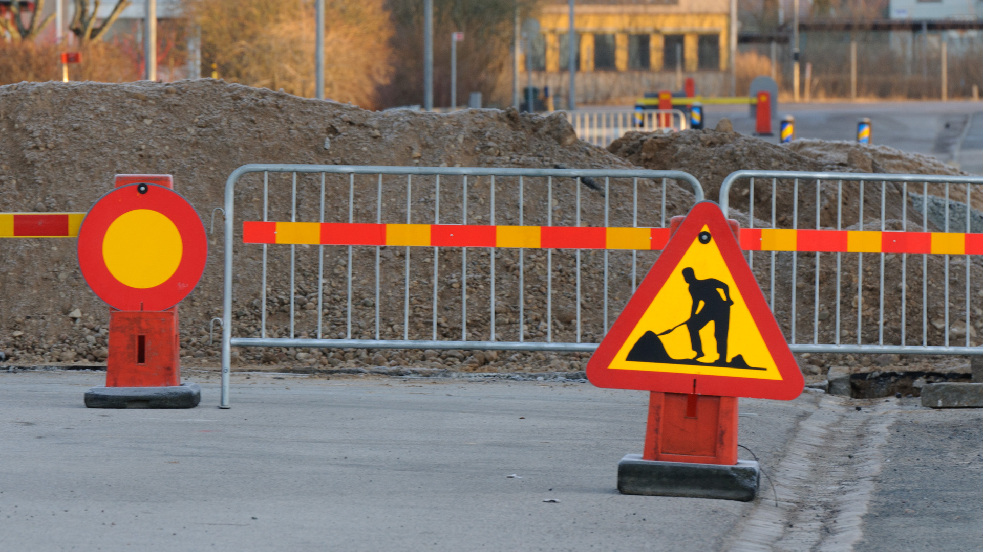 Vägskyltar som står framför väg grindar med en grushög bakom